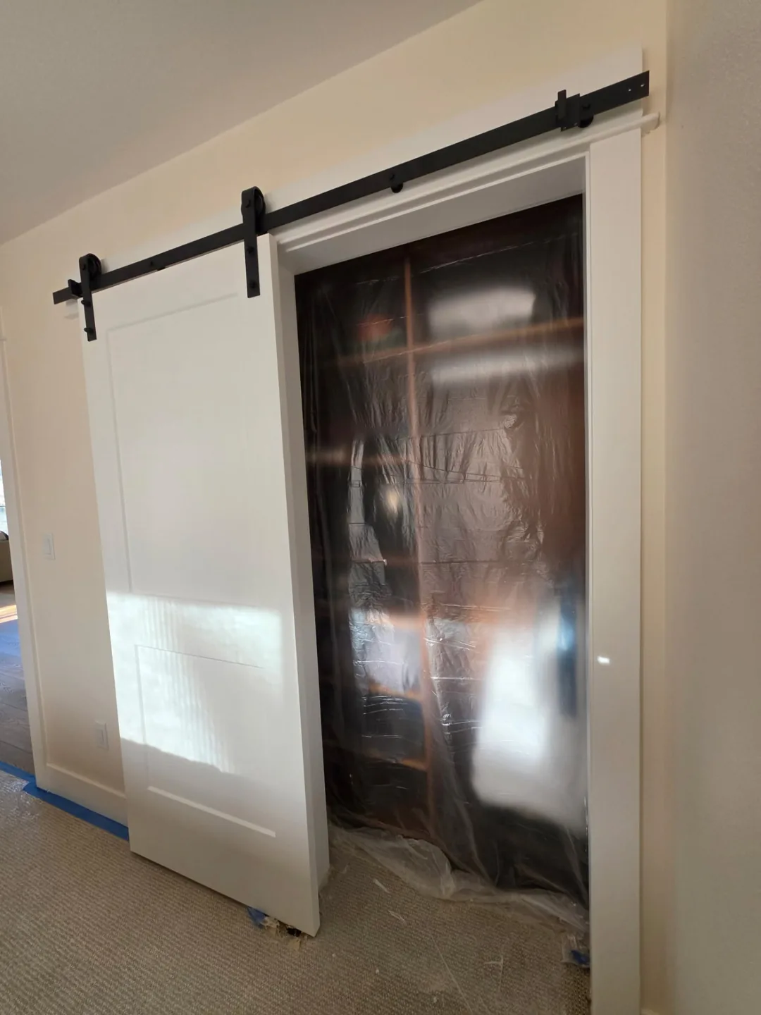 Interior sliding barn door with a wood finish and black track