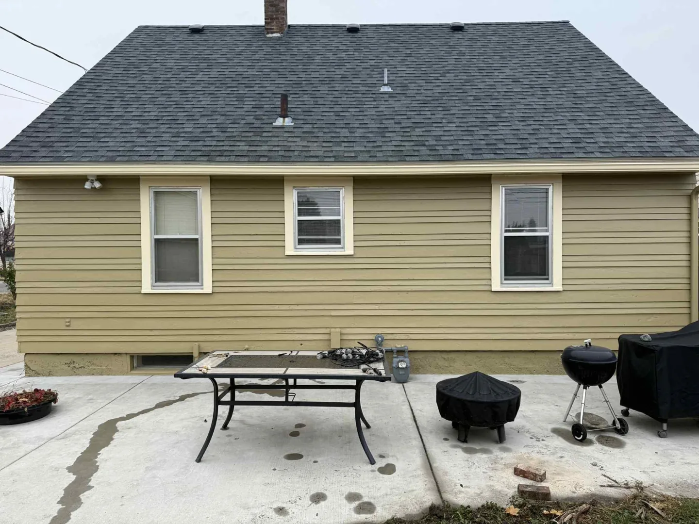 Back of a tan house with repainted siding and white trim
