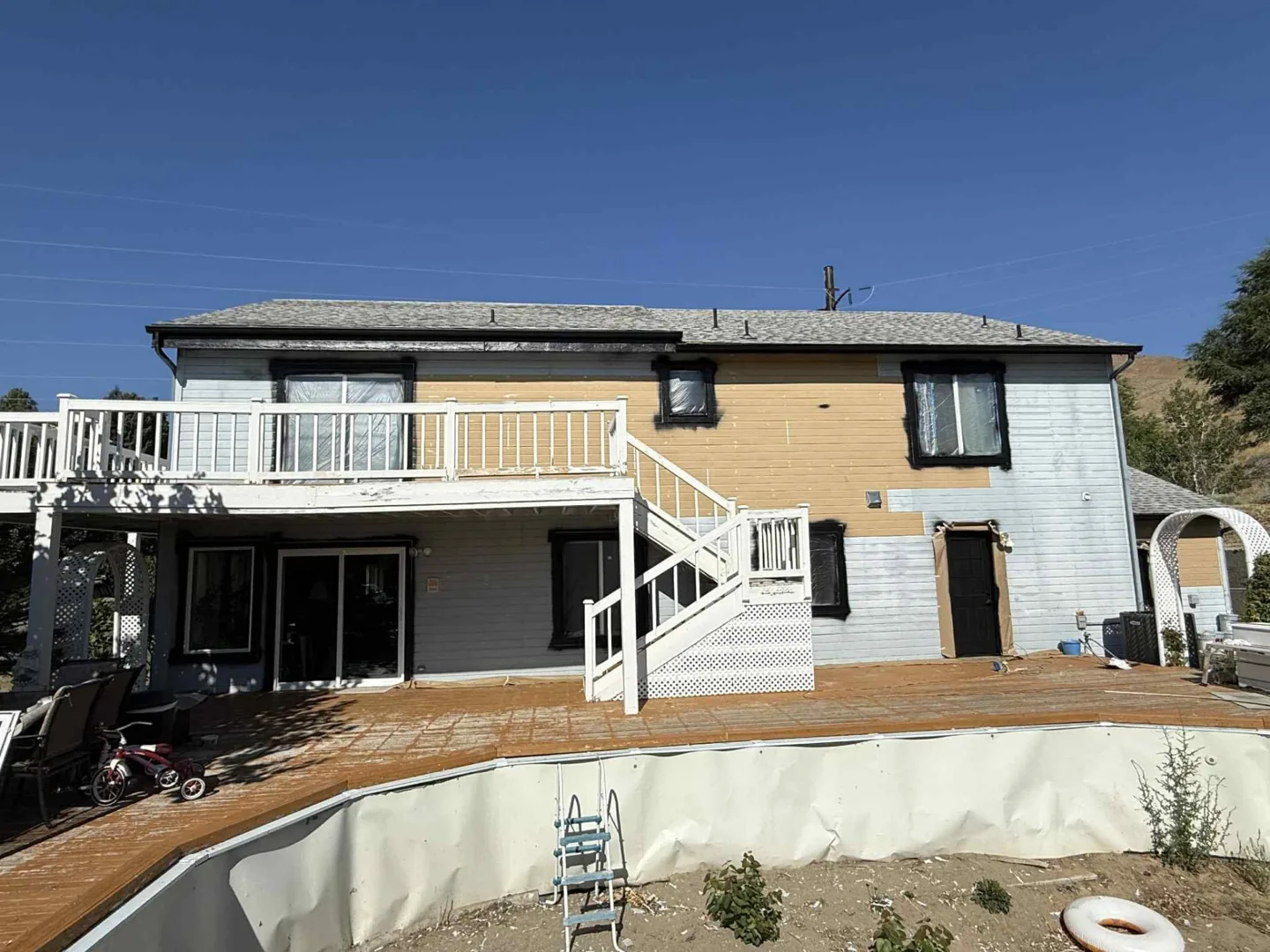 Two story house exterior with scaffolding and partly painted siding